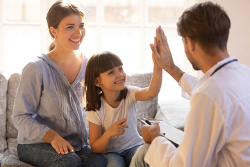 Happy cute child girl giving high five to male pediatrician