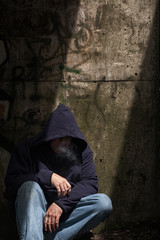 Homeless male in dark and rundown street location.