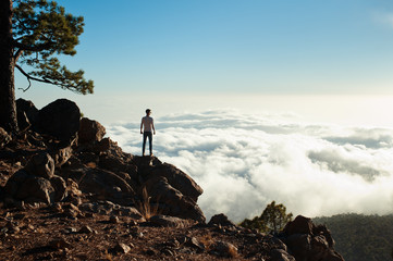 Back view of tourist boy enjoys the view on mountain top. Sky and clouds background. Leadership, travel concept.
