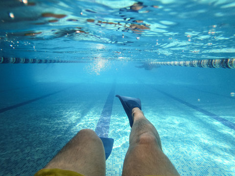 Man Swimming Underwater In Pool With Flippers