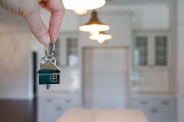 Hand holding Key to New House Inside New Construction