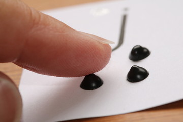 Close up of a finger feeling a raised dot that is part of the letter 'j' in braille.