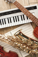Vertical top view of different musical instruments: synthesizer, guitar, saxophone and violin lying...