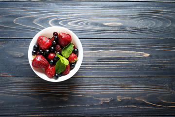 Fruit salad with  currant, strawberry and mint on wooden background  with space for text. Top view.
