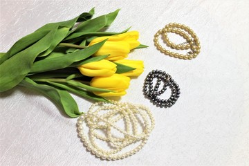 tulips and pearl necklace on white background