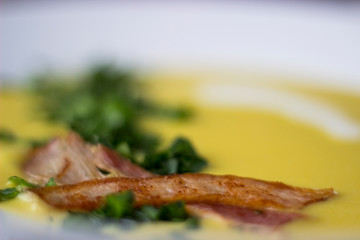 Pea soup with pieces of bacon, parsley and onion in a bowl on a dark background. Pea cream soup. Macro.