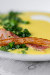 Pea soup with pieces of bacon, parsley and onion in a bowl on a dark background. Pea cream soup. Macro.