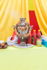 Samovar with a bunch of dryers and bottles of ketchup for barbecue on a yellow-red background