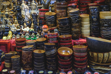 Different hand made bowls and various statues of the gods of luck, a fine souvenirs selling on a local Bang Niang Night Market in Khao Lak, Thailand.