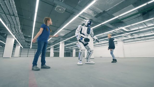 A boy and a girl are teasing a human-like droid