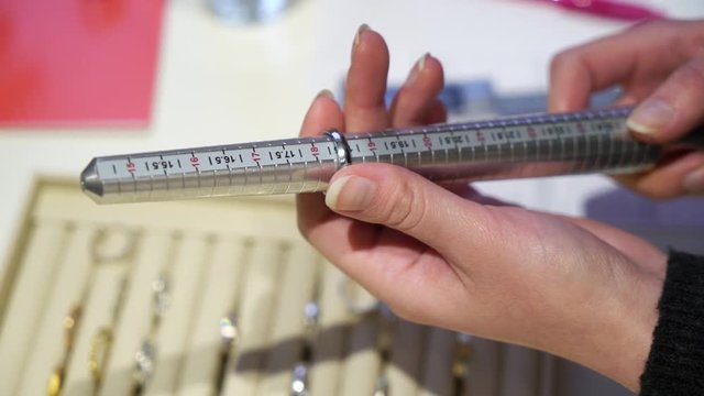 Person choosing size of jewelry ring, trying on a finger