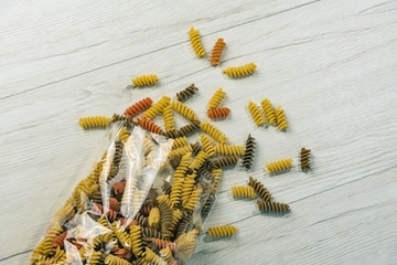 Naklejka premium Raw uncooked three-colored Fusilli on white wood table.