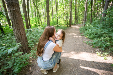 Nature, family, people concept - Family and nature concept - Beautiful Mom kisses her little daughter on the cheek