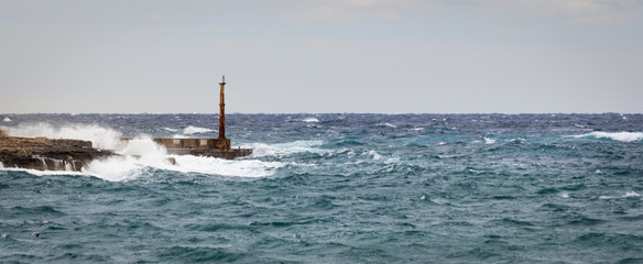 Fototapeta premium Tower, Breakwater and Lighthouse withstand raw sea and high waves. Sliema, Malta, Europe