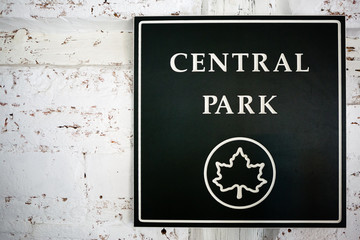 A wall with a dark green sign of central park