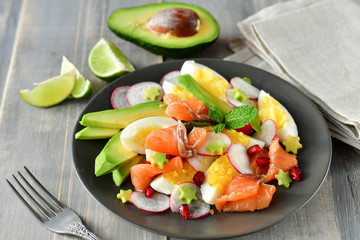 Salad with avocado and with salmon, eggs and radish. Decorated with mint leaf and pomegranate....