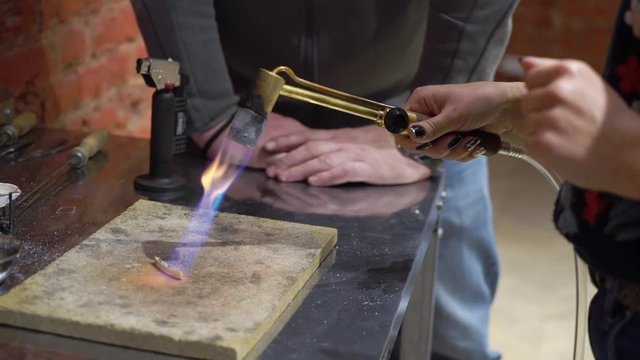 Goldsmith working with a unfinished ring using fire
