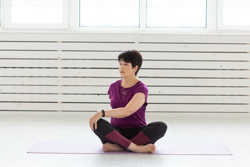 Healthy lifestyle, people and sport concept - Middle aged woman doing yoga