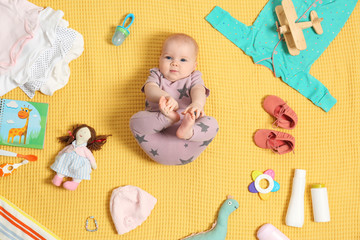 Cute little baby with clothing and accessories on color blanket, top view