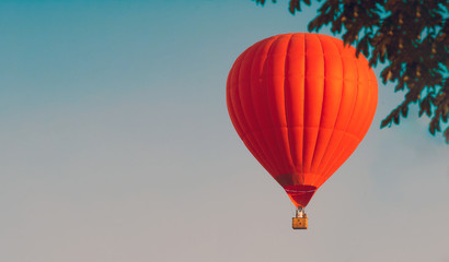 Obraz premium Red balloon in the sky. Aerostat. People in the basket. Fun. Summer entertainment. Romantic adventures. Modern toned photo. Retro colors.