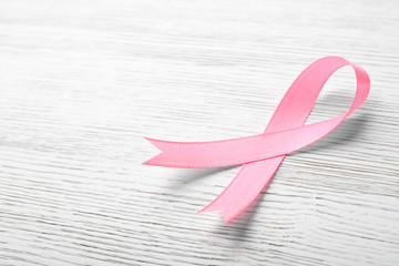 Pink ribbon on wooden background, space for text. Breast cancer awareness concept