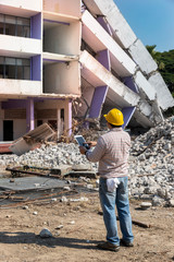 Engineer holding tablet is checking for destruction, demolishing building.