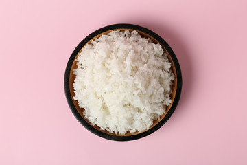 Fototapeta na wymiar Bowl of boiled rice on color background, top view
