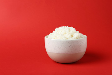 Bowl of boiled rice on color background. Space for text