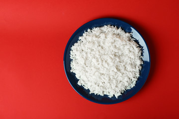 Plate of boiled rice on color background, top view with space for text