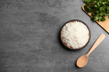 Boiled rice in bowl served on grey table, top view with space for text