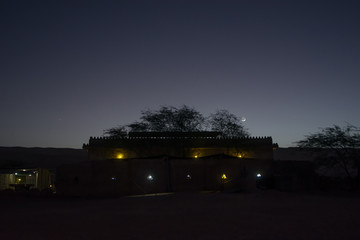 Obraz premium Silhouette of a residential building in the desert in the light of the moon