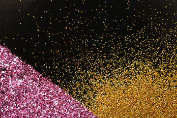 Gold and rose glitter on black background, top view with space for text