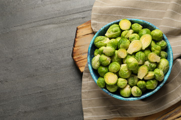 Bowl with fresh Brussels sprouts on grey table, top view. Space for text