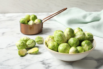 Bowl with fresh Brussels sprouts on marble table. Space for text