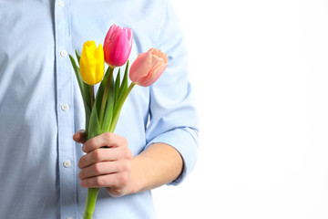 Man holding beautiful spring tulips on light background, closeup. International Women's Day