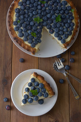 Blueberry Tart. Homemade piece of berry tart, cake with cream. Fresh sweet dessert with fruit. Top view. wooden, rustic background.