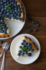 Blueberry Tart. Homemade piece of berry tart, cake with cream. Fresh sweet dessert with fruit. Top view. wooden, rustic background.