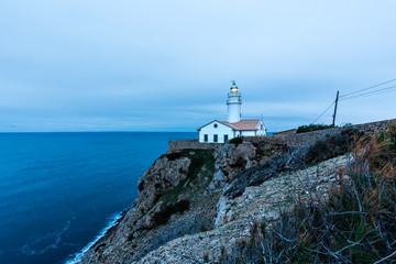Fototapeta na wymiar Leuchtturm auf einem Felsen umringt vom Meer, zur blauen Stunde