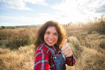 Travel, tourism and nature concept - Young woman fooling around taking selfie on field