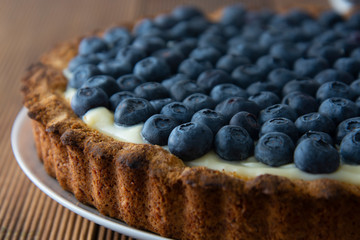 Close up blueberry tart or cake with cream and berries. Fresh sweet dessert with fruits. Homemade food, wooden, rustic background.