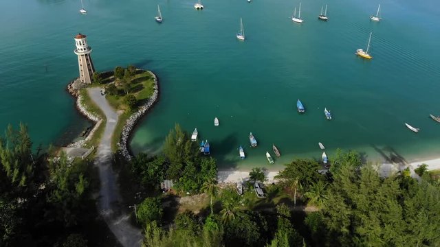 Aerial Til Down View Of A Lighthouse And Luxury Yachts With Turquoise Ocean 4K