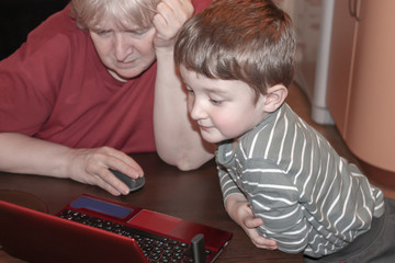 Fototapeta na wymiar Grandson and grandmother using a computer at home
