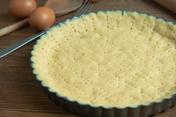 Raw tart dough, base pastry for pie, tart or cake. Cooking healthy dessert in baking pan. Rustic, wooden background.