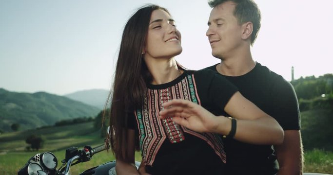 Details of a young charismatic couple spending a lovely time together in the middle of amazing landscape behind of their motorcycle