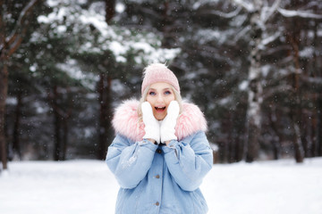 Fototapeta na wymiar Surprised woman on a winter background in warm clothes.