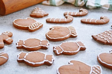 Obraz na płótnie Canvas Home-baked gingerbread is decorated with frosting on a kitchen surface with a baking sheet and baking paper - Christmas concept with home-baked cookies in the kitchen