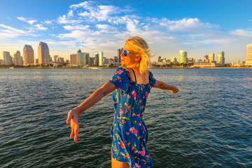 Happy tourist woman looking at San Diego Downtown skyline with skyscrapers in California, USA from Coronado Island. Travel and tourism american concept. Waterfront and urban cityscape in San Diego Bay