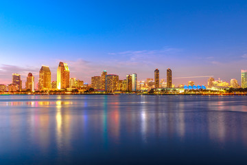 Panoramic landscape of San Diego skyline with illuminated skyscrapers reflecting in San Diego Bay...