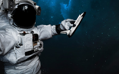 Astronaut with toy Shuttle in his hand. Science fiction art. Elements of this image furnished by...