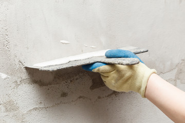 girl in blue gloves. review only a limb. putty putty on the wall. close-up